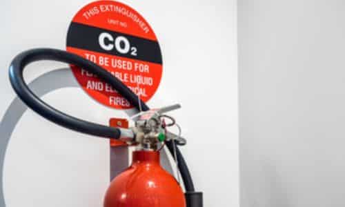 Immagine di un estintore co2 su una parete bianca e con il cartellino della descrizione