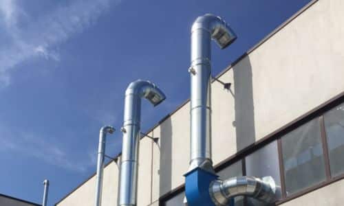 Tubi in acciaio da cui esce il fumo aspirato dell'impianto di aspirazione industriale
