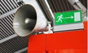 Immagine di un autoparlante con vicino la segnaletica di uscita di emergenza